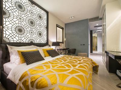 Modernes Hotelzimmer mit gelbem Bettüberwurf und stilvoller Beleuchtung