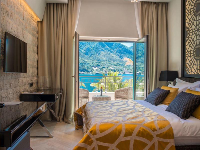 Gemütliches Hotelzimmer mit großem Fenster und Blick auf See und Berge.