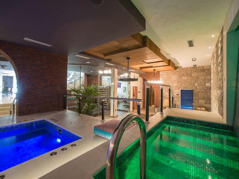 Moderner Wellnessbereich mit Whirlpool, beheiztem Pool und Steinen an den Wänden.