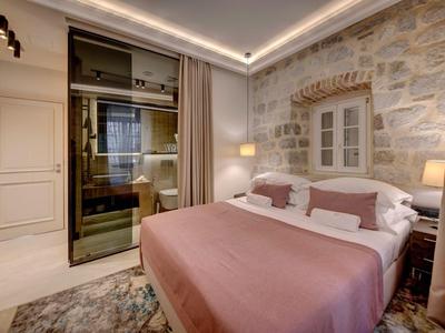 Modernes Hotelzimmer mit Steinhintergrund, großem Bett, sanfter Beleuchtung und Teppichboden.