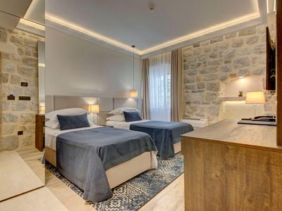 Modern eingerichtetes Hotelzimmer mit zwei Betten, Steinwand und weicher Beleuchtung.