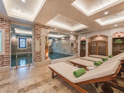Luxuriöser Wellnessbereich mit beheiztem Pool, Liegestühlen und warmem Ambiente in einem Hotel.