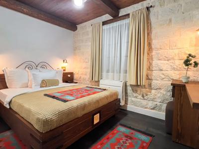 Gemütliches Hotelzimmer mit Doppelbett, Steinalkoven-Wand und Teppichboden.