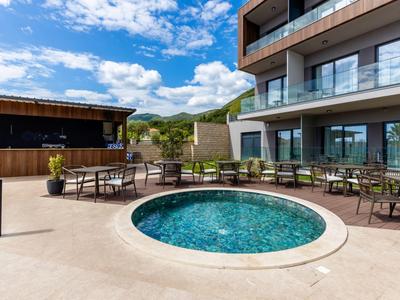 Rundes Pool mit klarem Wasser umgeben von Stühlen und Tischen neben einem modernen Gebäude.