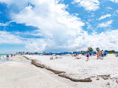Breiter Sandstrand mit Menschen, blauem Himmel und wolkigem Himmel am Meer.