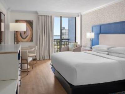 Modernes Hotelzimmer mit Doppelbett, Schreibtisch, Fernseher und großem Fenster mit Blick nach draußen.