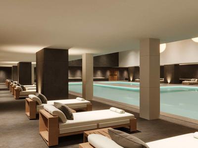 Moderner Wellnessbereich mit Schwimmbecken und Liegen in ruhiger Atmosphäre.