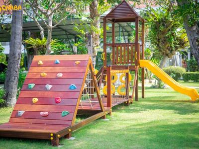 A colorful playground with climbing wall and yellow slide on green grass.