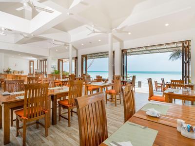 Bright, open restaurant with wooden furniture and sea view through large windows.