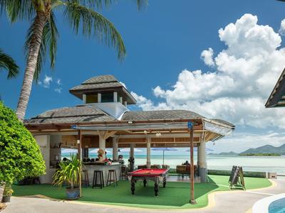 Open beach pavilion with bar, pool table, and sea view.