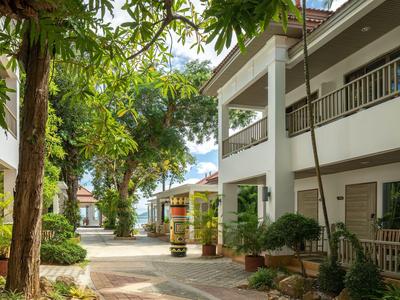 View of a quiet courtyard with trees and hotel buildings under a blue sky.
