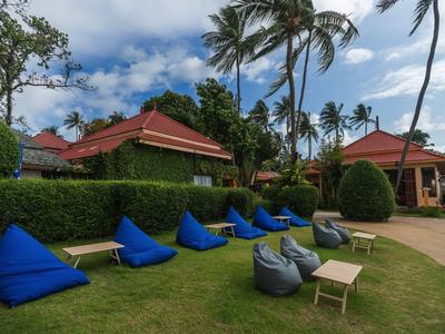 Garten mit blauen und grauen Sitzsäcken vor tropischen Bungalows und Palmen