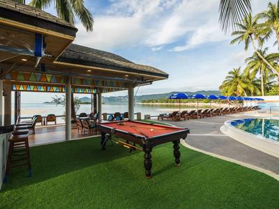 Billardtisch im Freien neben Pool und Sonnenliegen unter Palmen mit Meerblick
