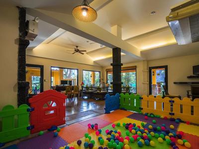 Kinderspielbereich mit buntem Ballpool und Holzzaun in einem hellen Raum mit großen Fenstern.