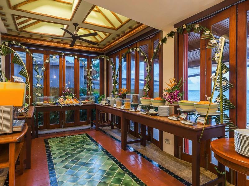 Großes Buffet mit Holzregalen, verschiedenen Speisen, Glasfenstern und grüner Dekoration.