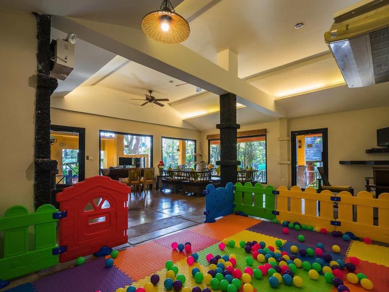 Heller Spielraum mit buntem Bällebad, farbigen Zäunen und großen Fenstern in gemütlicher Atmosphäre.