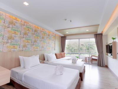 Camera d'hotel moderna con due letti, parete colorata e grande finestra con vista sul verde.