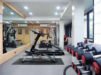 Moderner Fitnessraum mit Laufband, Hanteln und großen Spiegeln neben großen Fenstern.