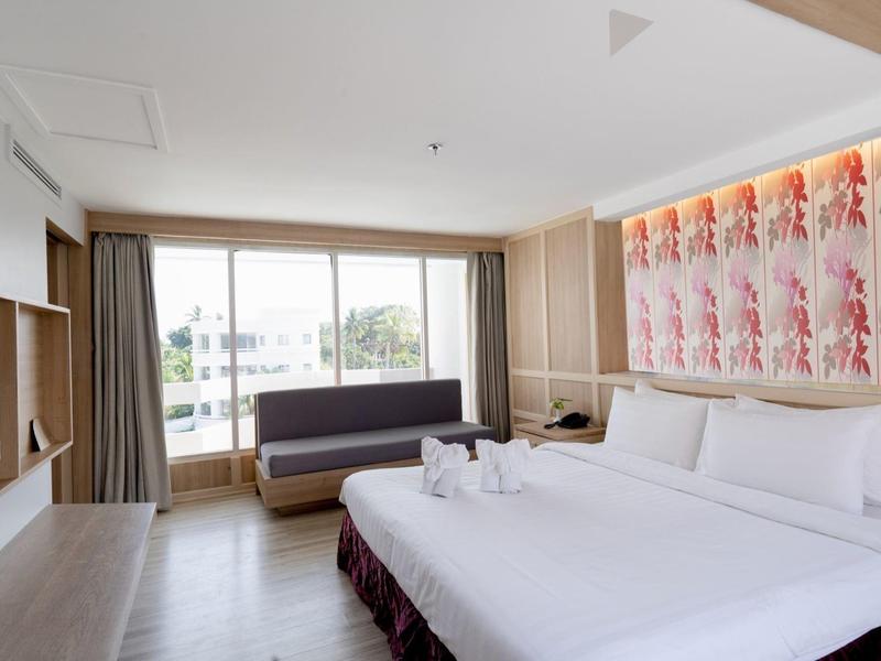 Camera d'hotel moderna con letto matrimoniale, divano e grande finestra con vista sul balcone.