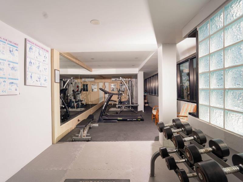 Sala fitness moderna con manubri, bilancieri e specchi in un hotel.