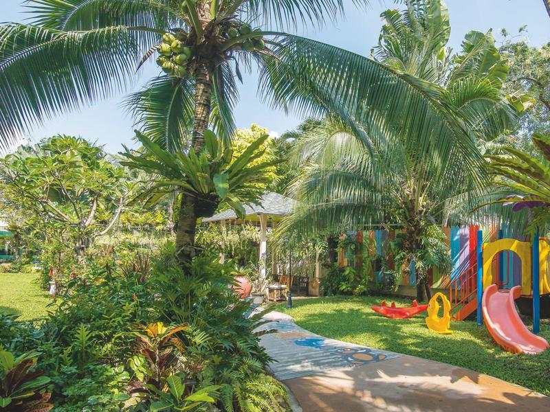 Un giardino con piante tropicali e un'area giochi colorata con scivoli.