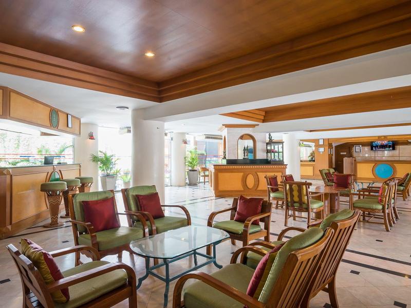 Ampia area lounge dell'hotel con mobili in legno e tavolini in vetro.