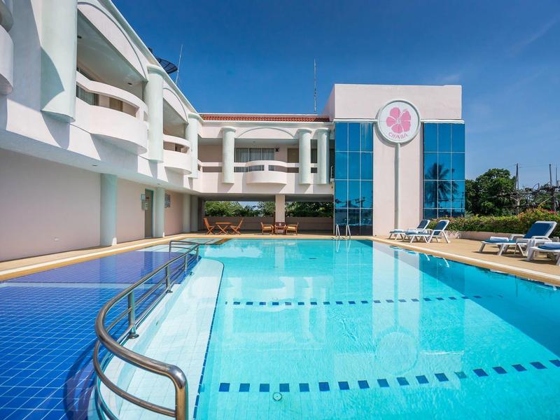 Piscina limpida accanto a un moderno hotel bianco sotto un cielo soleggiato.