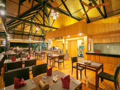 Innenraum eines warm beleuchteten Restaurants mit Holzmöbeln und hohen Decken.