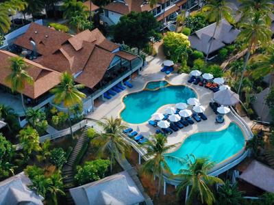 Vogelperspektive eines tropischen Resorts mit zwei geschwungenen Schwimmbädern und umgeben von Palmen.