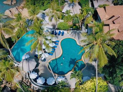 Vogelperspektive eines tropischen Hotelpools mit Palmen und Sonnenschirmen.