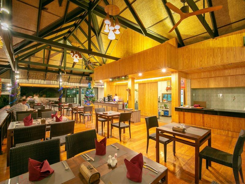 Innenraum eines warm beleuchteten Restaurants mit Holzmöbeln und hohen Decken.