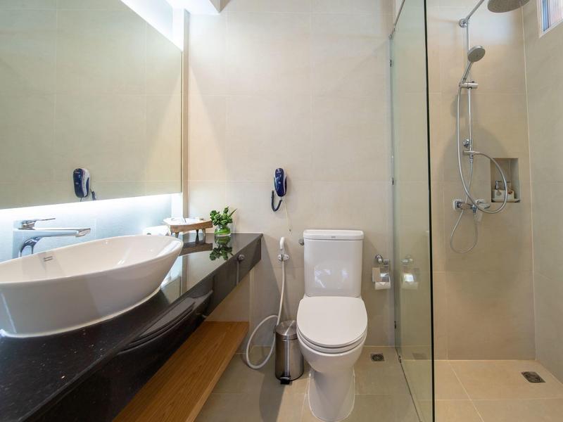 Moderner, heller Badraum mit Glasdusche, weißer Toilette, Waschbecken und großem Spiegel.