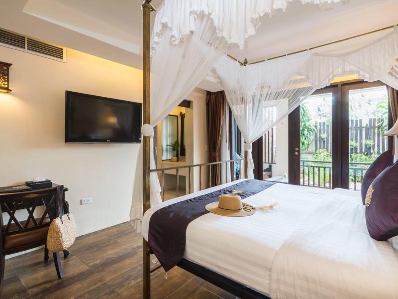 Habitación de hotel elegante con cama con dosel, televisor y acceso al área del jardín.