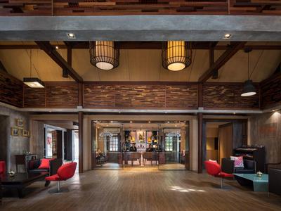 Ampia hall dell'hotel con pavimento in legno, aree salotto accoglienti e illuminazione rustica.