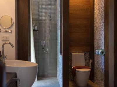 Bagno moderno con lavabo e zona doccia e toilette separate in tonalità calde di legno.