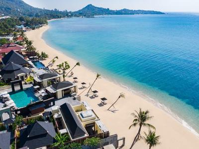 Resort di lusso sulla spiaggia con piscine, palme e sabbia bianca lungo il mare turchese.