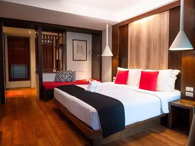 Modernes Hotelzimmer mit großem Bett, rotem Akzent und Holzfußboden.