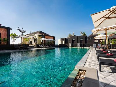 Moderner Außenpool mit Liegestühlen und Sonnenschirmen unter klarem blauem Himmel.