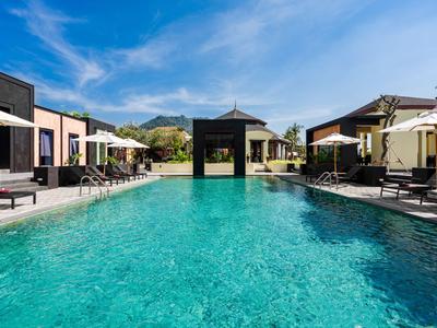 Moderner Hotelpool mit Liegestühlen und Sonnenschirmen bei klarem Himmel.