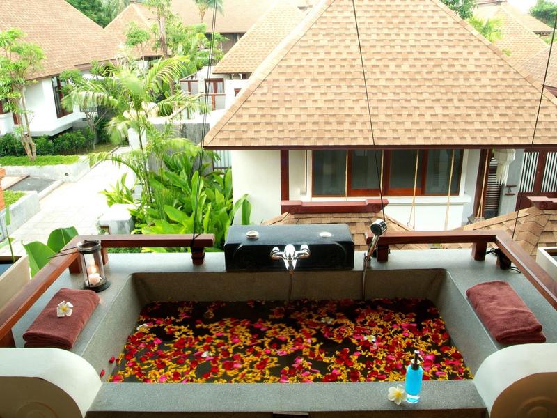 Vista di una terrazza con una vasca di fiori davanti a un bungalow in un resort tropicale.