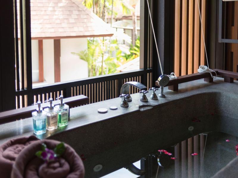 Vasca da bagno di lusso con petali, oli aromatici e asciugamano nel bagno dell'hotel.