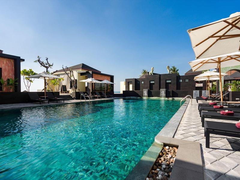 Area piscina moderna con lettini e ombrelloni sotto un cielo limpido.