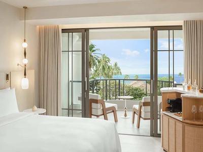 Modernes Hotelzimmer mit Doppelbett und Blick auf Balkon, Meer und Palmen.