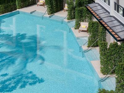 Moderner Außenpool mit hellblauem Wasser und Liegestühlen in einem grünen, gepflegten Bereich