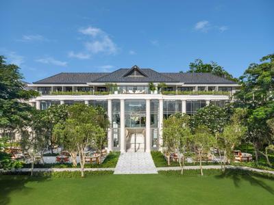 Großes Hotelgebäude mit weißer Säulenfront, grünem Rasen und blauem Himmel.