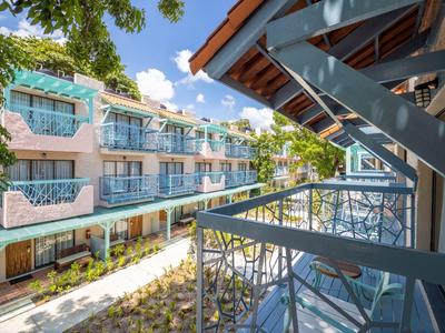 Pohled z balkonu na moderní hotelovou budovu se skleněnými zábradlími a modrými akcenty.