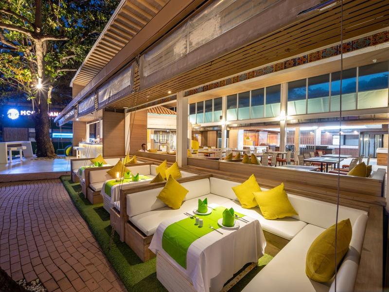 Pohodlné venkovní posezení s bílými pohovkami a žlutými polštáři u hotelu