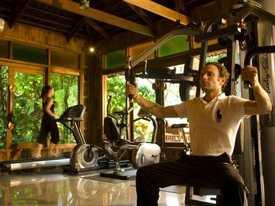 Person trainiert an Fitnessgeräten in hellem, modern eingerichtetem Fitnessraum mit großen Fenstern.