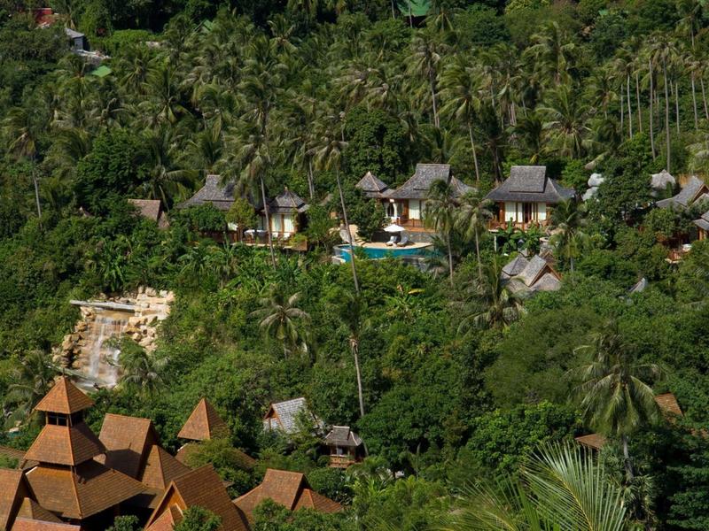 Ein Luxushotel mit Pool umgeben von dichtem, grünem Dschungel auf einem hügeligen Terrain.