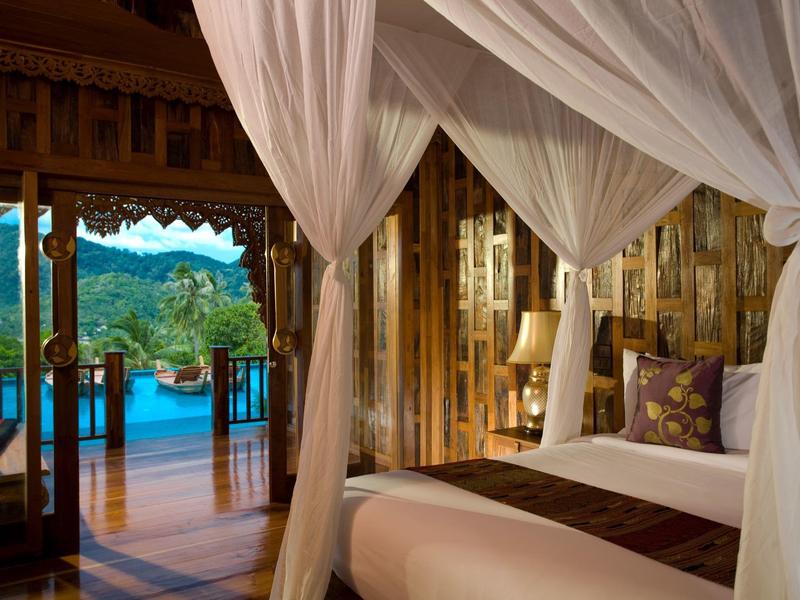 Luxuriöses Schlafzimmer mit Himmelbett und Blick auf eine Holzterrasse mit Pool und Berglandschaft.